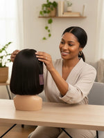 Woman styling a Unique Style 2 Envy Inc short black bob lace front human hair wig on a mannequin head in a home studio.